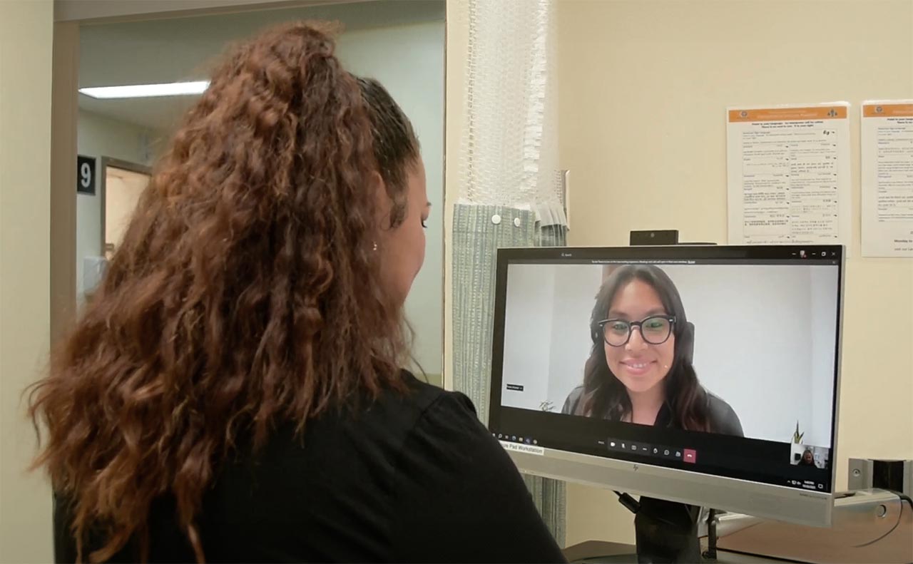 A nurse conducts a telehealth interview with a woman on her monitor